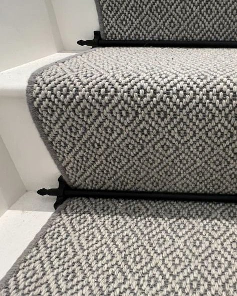 A bespoke stair runners supplied and installed by Flooring 4 You Ltd in Cheshire - it's made from fibre wool flatweave classic diamond with whipped edges and black stair rods to finish